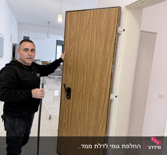 אדם מחזיק דלת עץ חדשה מותקנת